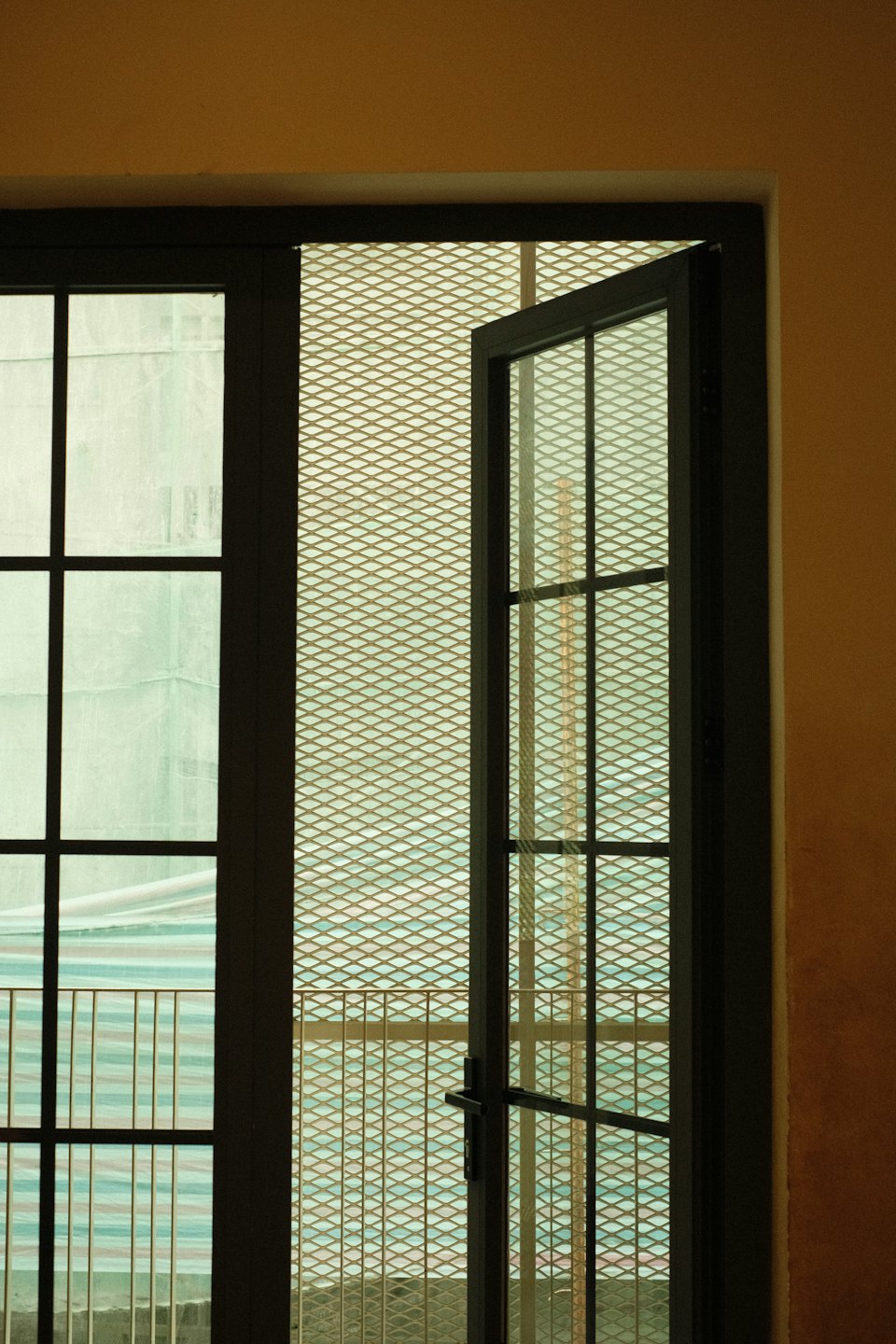 Una porta di vetro socchiusa su un muro color oro-marrone.